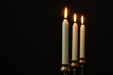 Photo of Burning candles on black background. Space for text