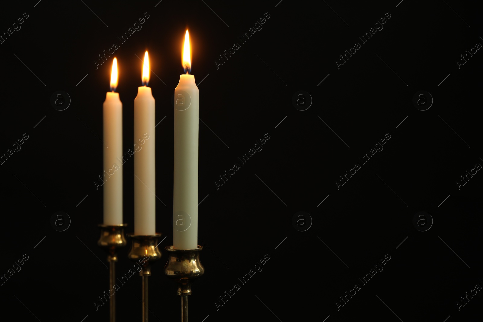 Photo of Burning candles on black background. Space for text