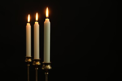 Photo of Burning candles on black background. Space for text