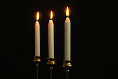 Photo of Many burning church candles on black background