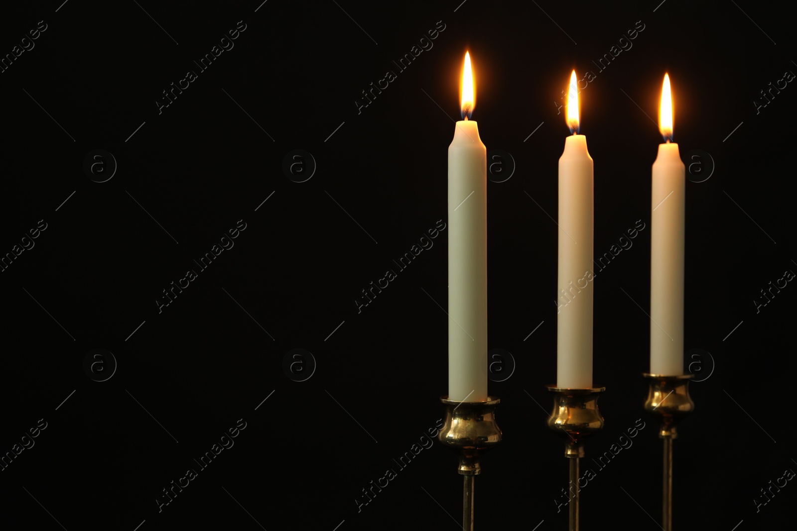 Photo of Many burning candles on black background. Space for text
