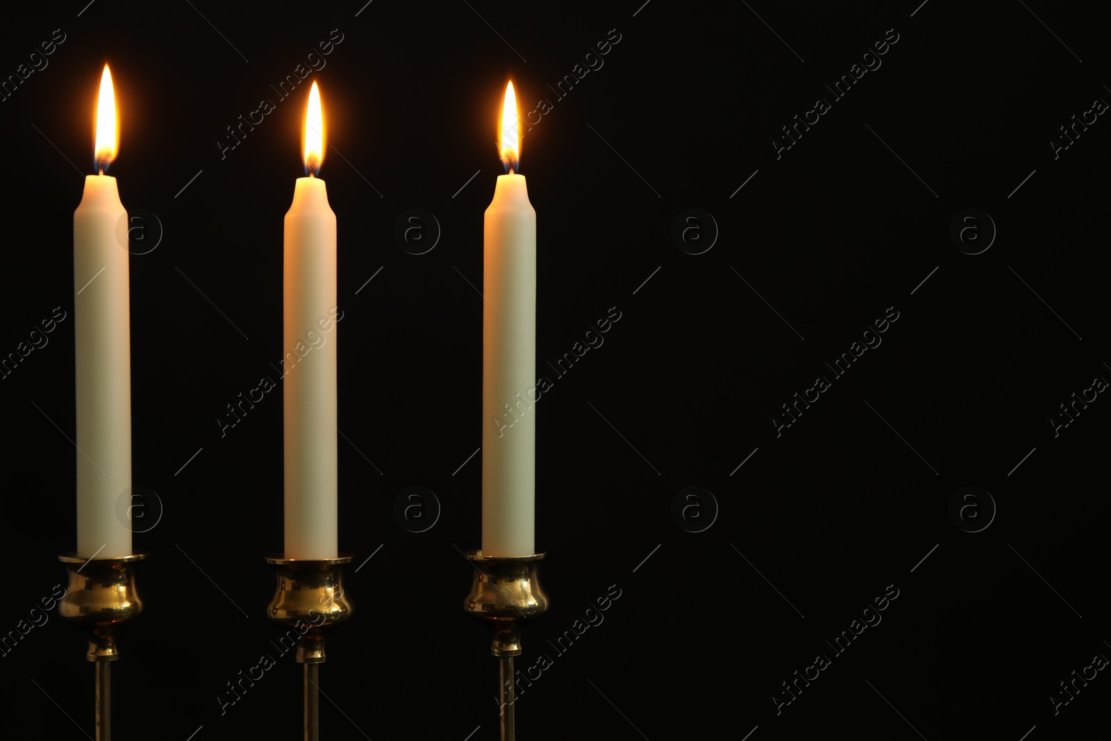 Photo of Many burning candles on black background. Space for text