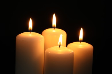 Many burning candles on black background, closeup