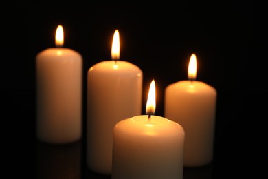 Many burning candles on black background, closeup