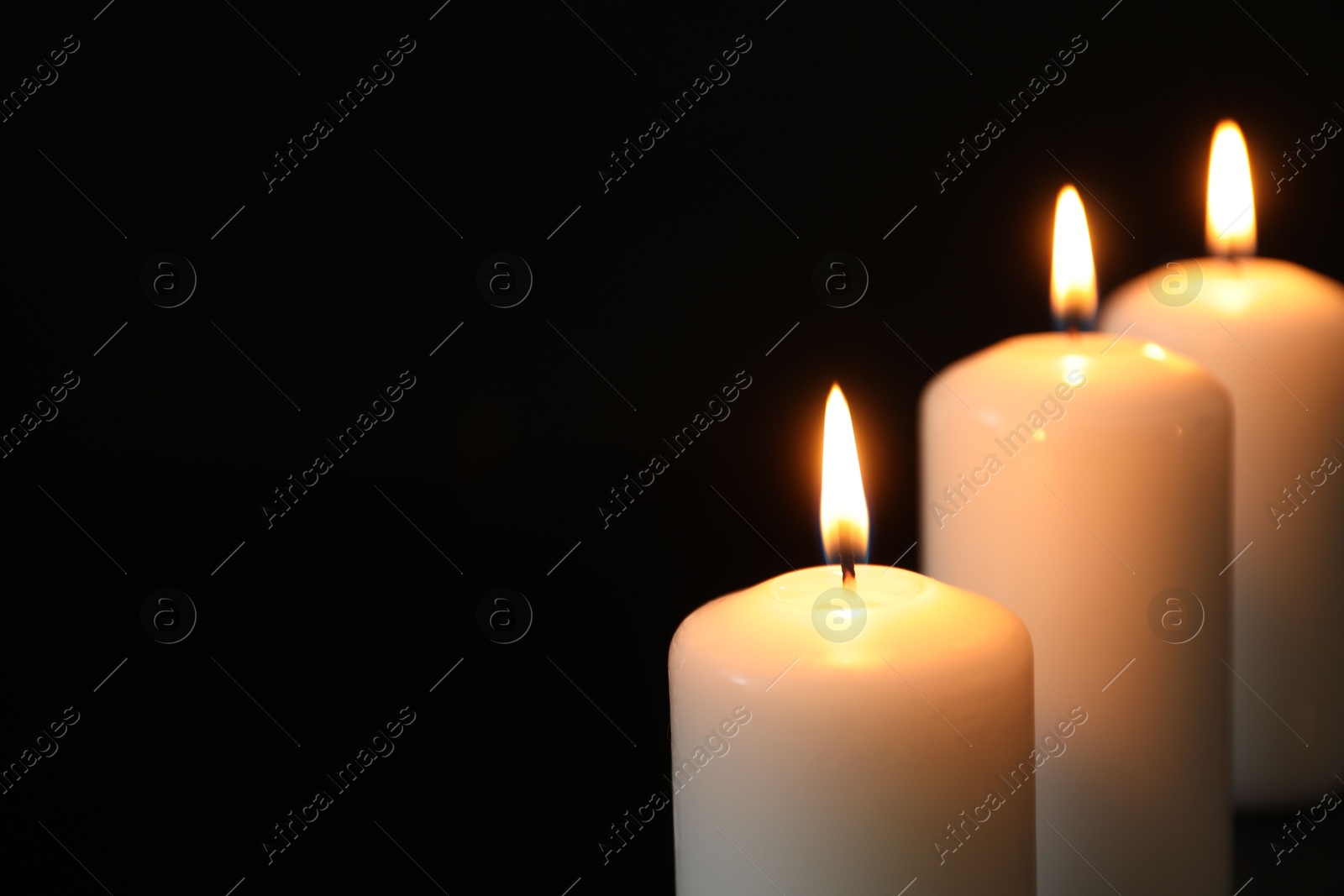 Photo of Many burning candles on black background, closeup. Space for text