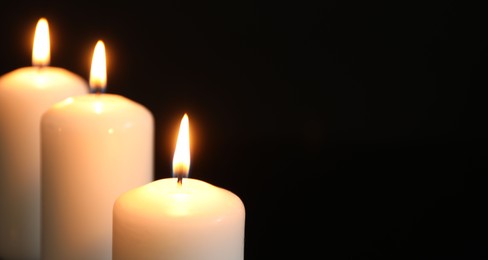 Many burning candles on black background, closeup. Space for text