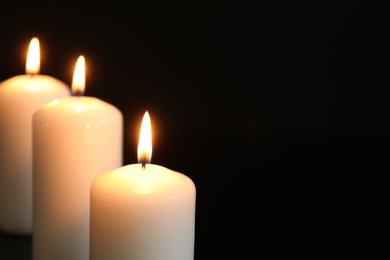 Photo of Many burning candles on black background, closeup. Space for text