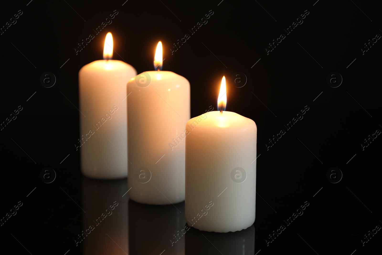 Photo of Many burning candles on mirror surface against black background