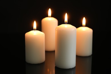 Many burning candles on mirror surface against black background