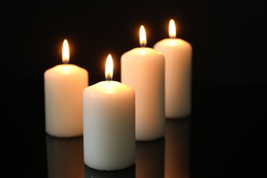 Photo of Many burning candles on mirror surface against black background