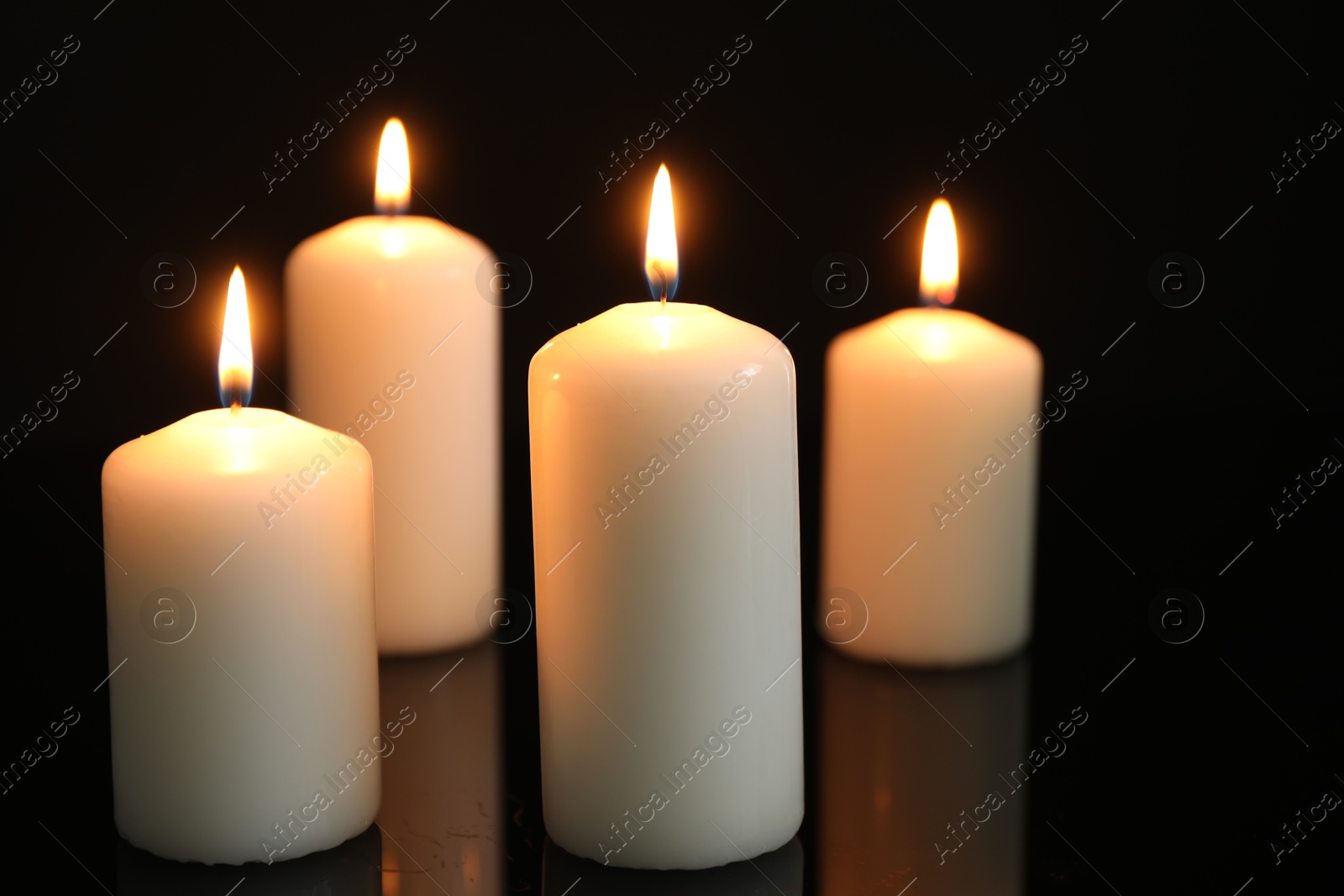 Photo of Many burning candles on mirror surface against black background