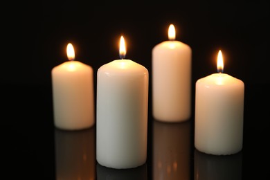 Photo of Many burning candles on mirror surface against black background