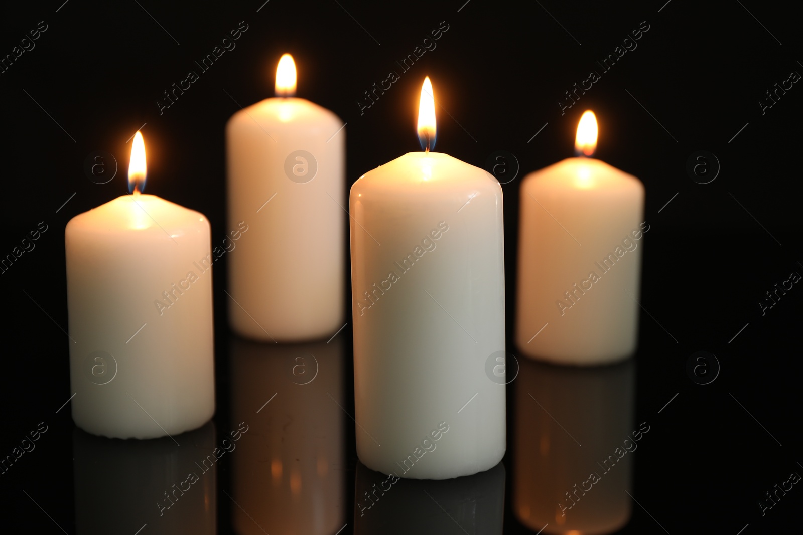Photo of Many burning candles on mirror surface against black background