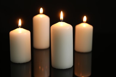 Many burning candles on mirror surface against black background