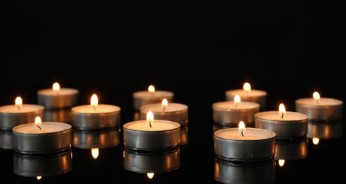 Many burning tealight candles on mirror surface against black background. Banner design