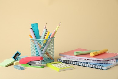 Bright stapler and other stationery on beige background, space for text