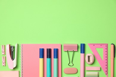 Flat lay composition with notebook, stapler and different stationery on green background, space for text