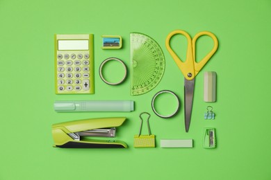 Flat lay composition with stapler and different stationery on green background