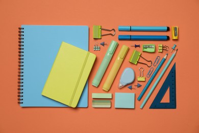 Flat lay composition with notebooks and different stationery on orange background