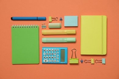 Flat lay composition with notebooks and different stationery on orange background