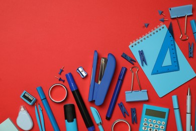 Flat lay composition with notebook, stapler and different stationery on red background, space for text