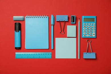 Flat lay composition with notebook and different stationery on red background