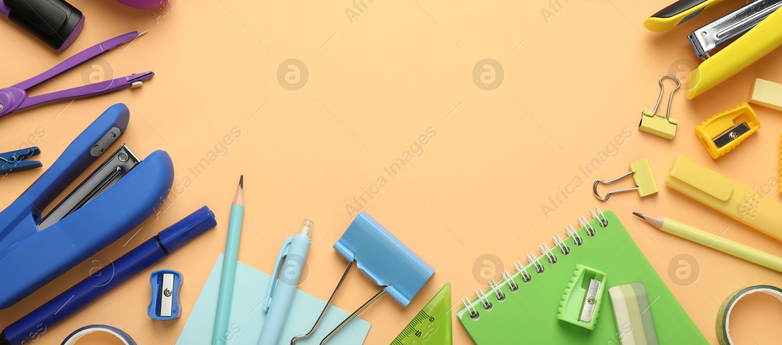 Photo of Flat lay composition with notebook, stapler and different stationery on pale orange background, space for text