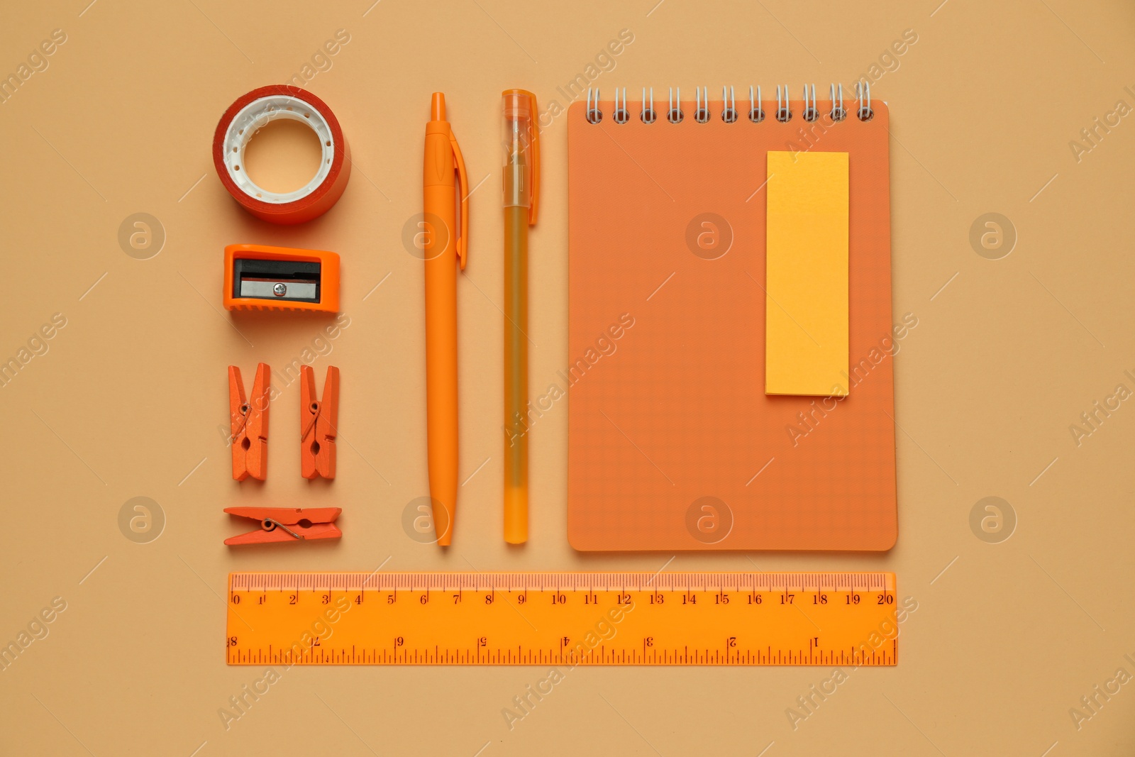 Photo of Flat lay composition with notebook and different stationery on pale orange background