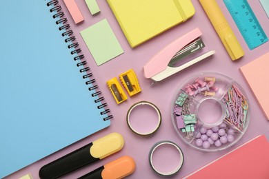 Flat lay composition with notebooks, stapler and different stationery on violet background