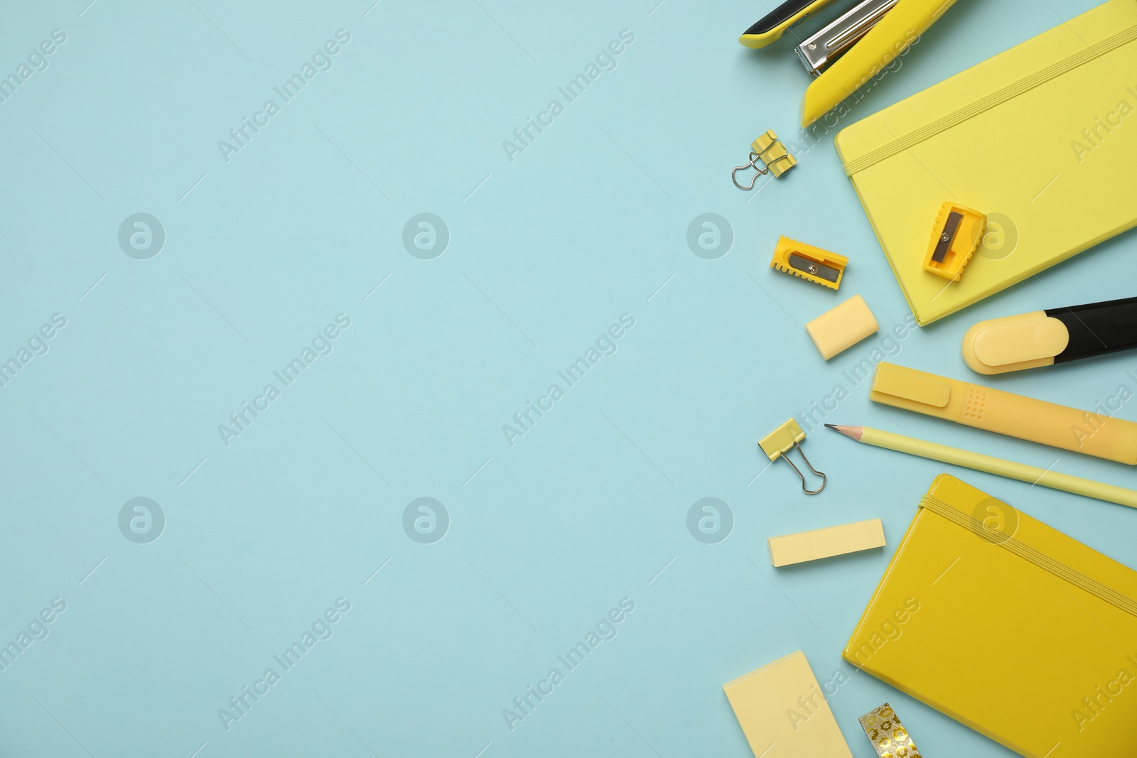 Photo of Flat lay composition with notebooks, stapler and different stationery on light blue background, space for text