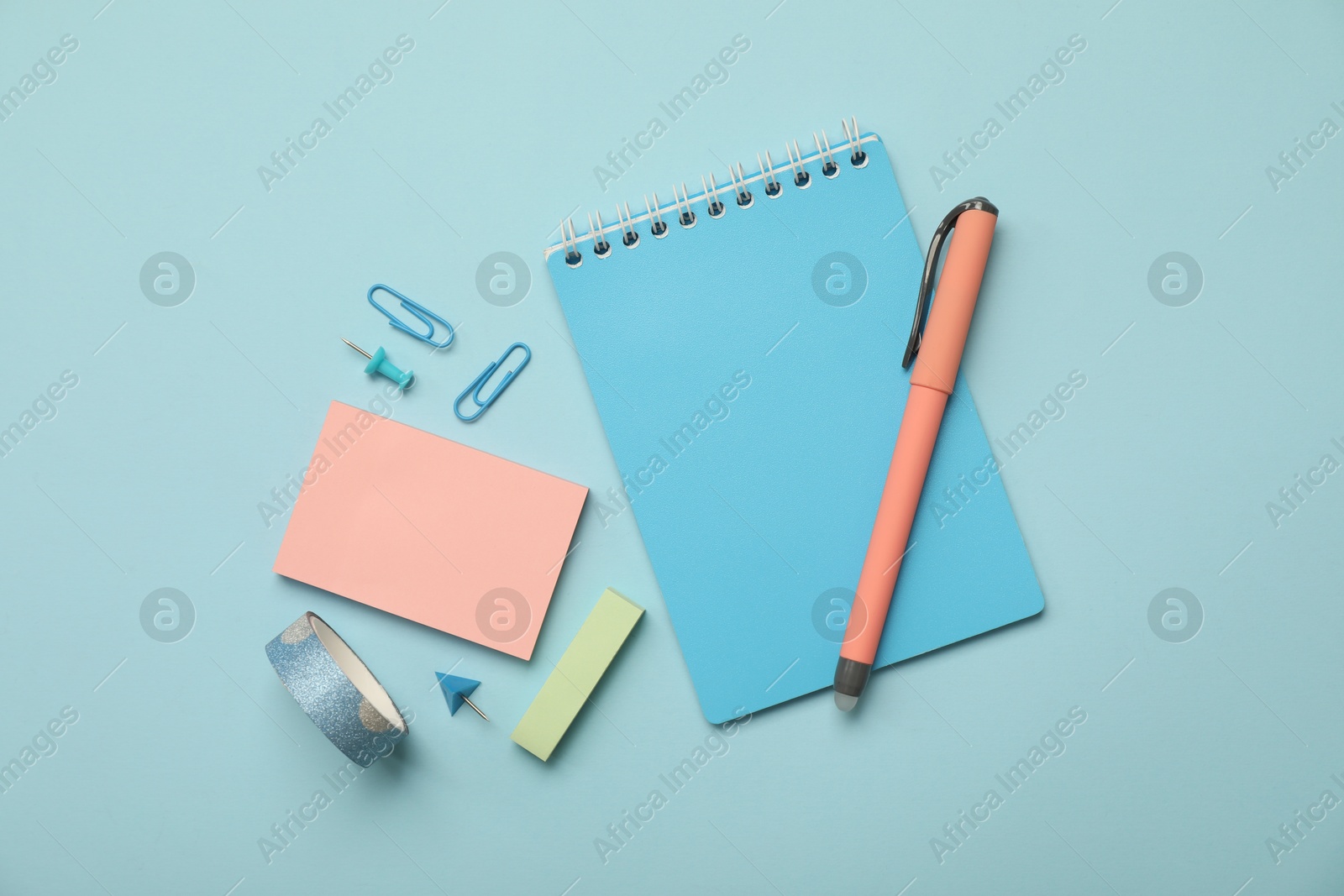 Photo of Flat lay composition with notebook and different stationery on light blue background