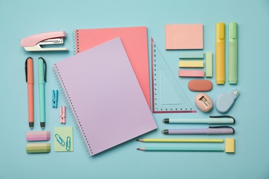 Flat lay composition with notebooks, stapler and different stationery on light blue background