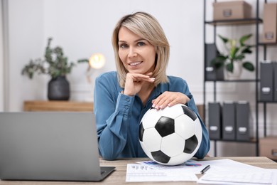 Photo of Smiling woman with soccer ball at table in office