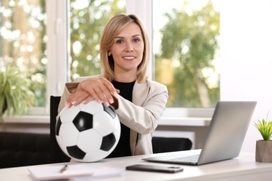 Photo of Smiling woman with soccer ball at table in office