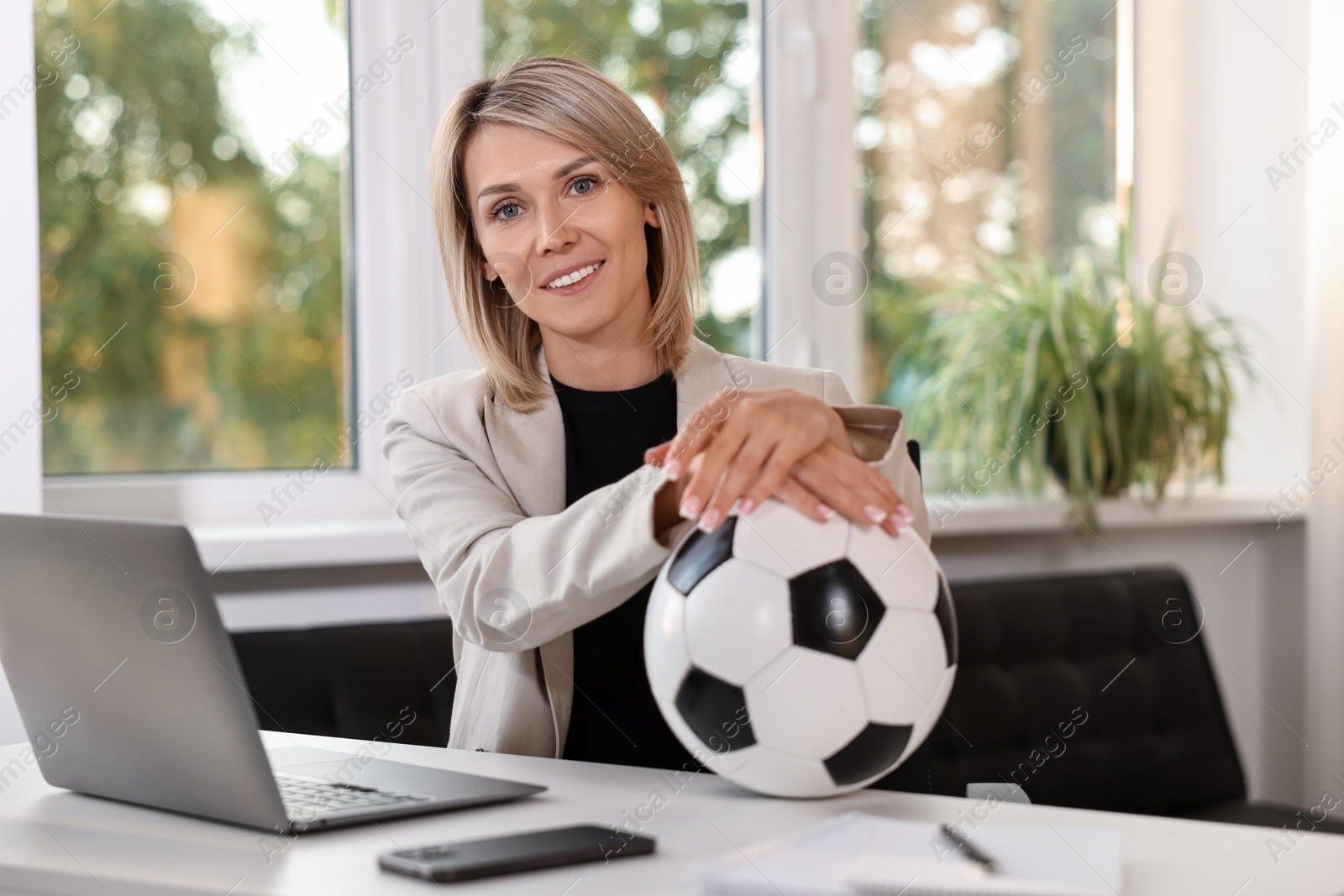 Photo of Smiling woman with soccer ball at table in office