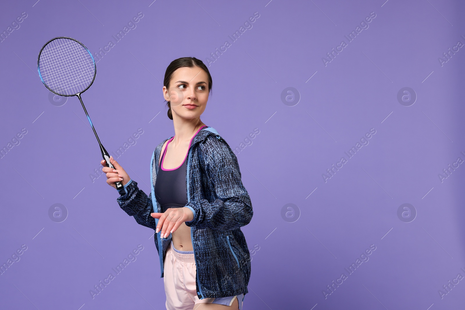 Photo of Young woman with badminton racket on purple background, space for text