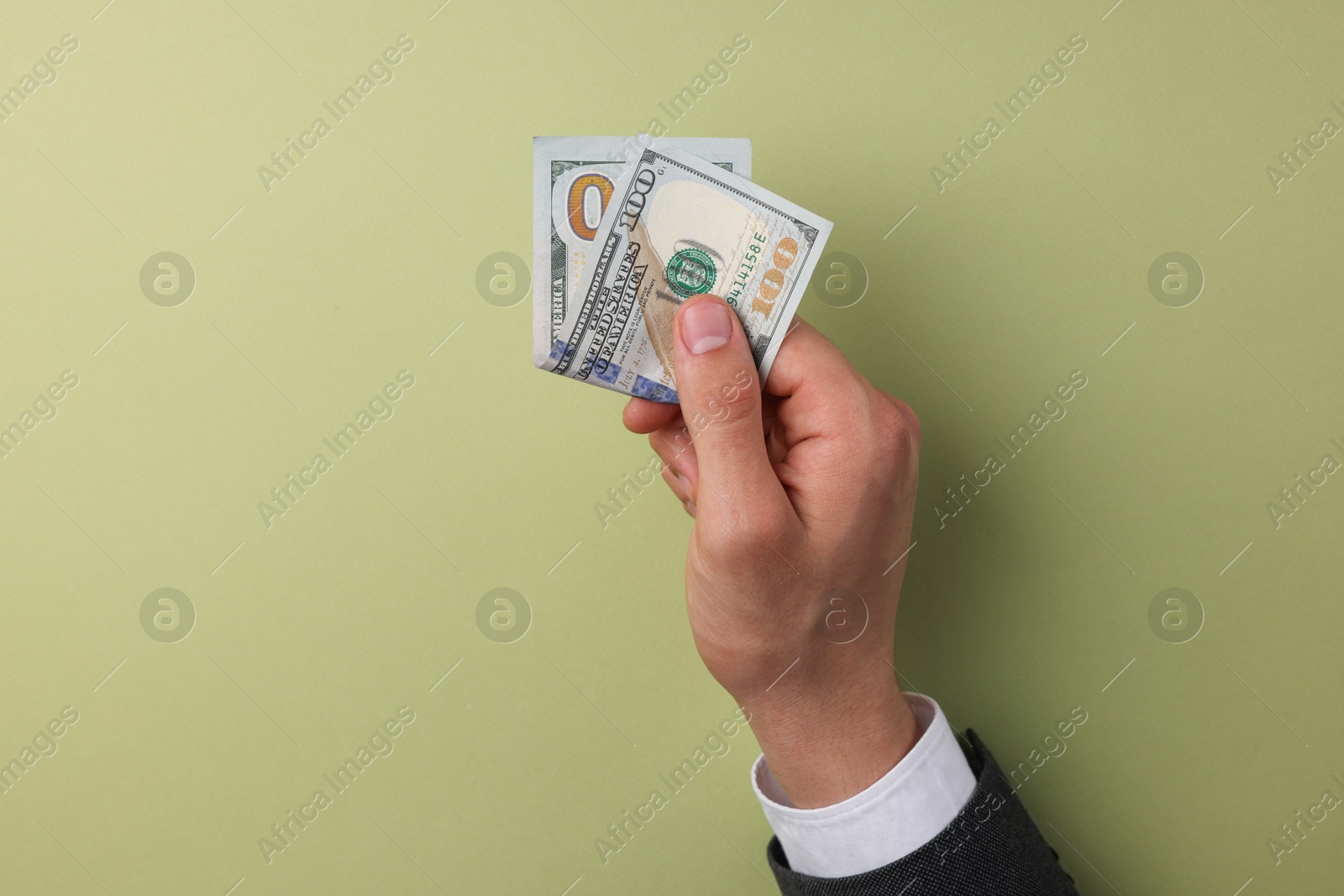 Photo of Money exchange. Man holding dollar banknotes on olive background, top view. Space for text