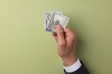 Photo of Money exchange. Man holding dollar banknotes on olive background, top view. Space for text