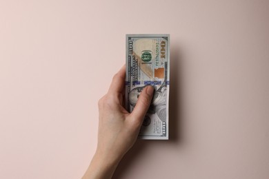 Photo of Money exchange. Woman holding dollar banknotes on beige background, top view