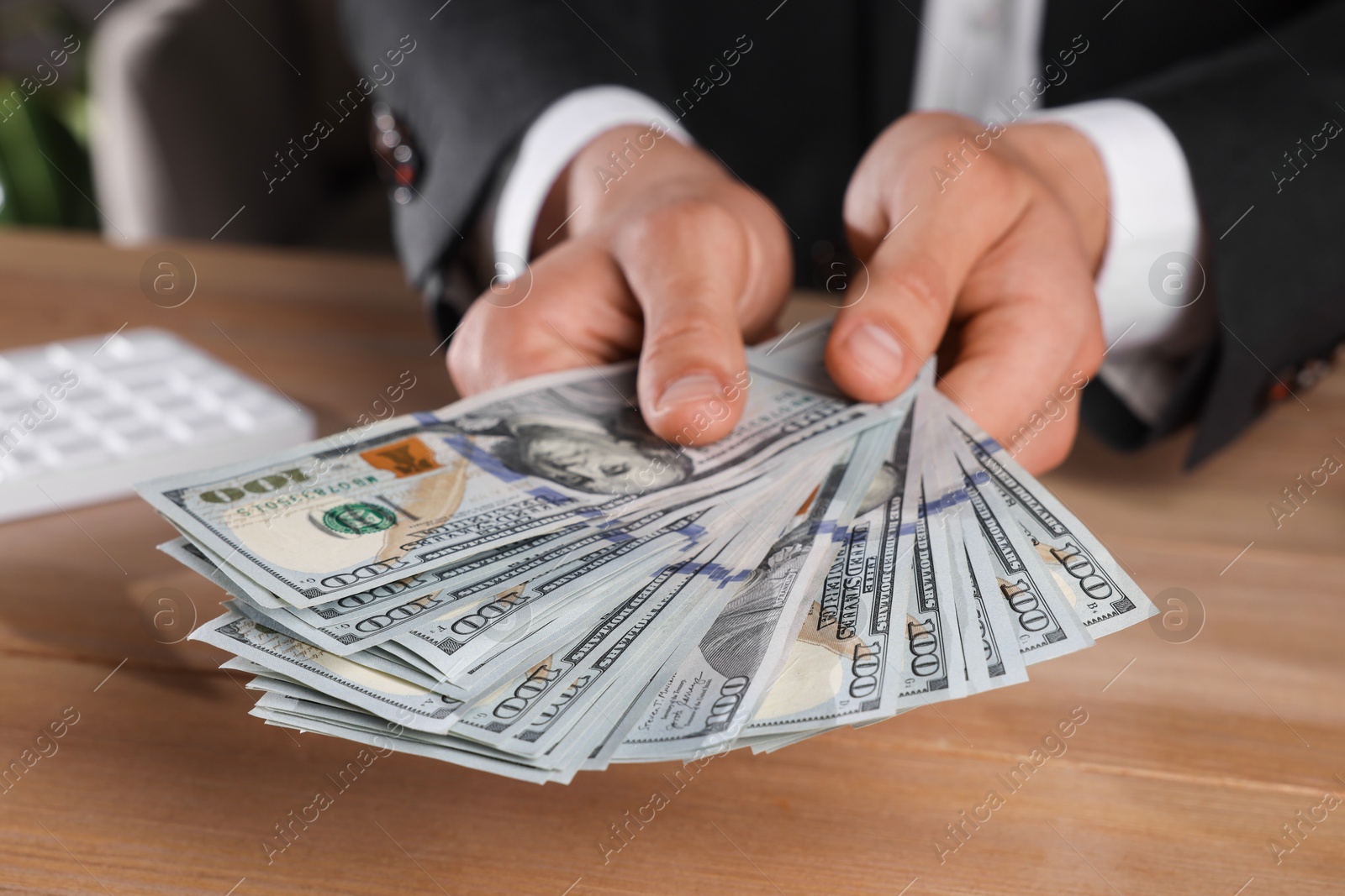 Photo of Money exchange. Man counting dollar banknotes at wooden table, closeup