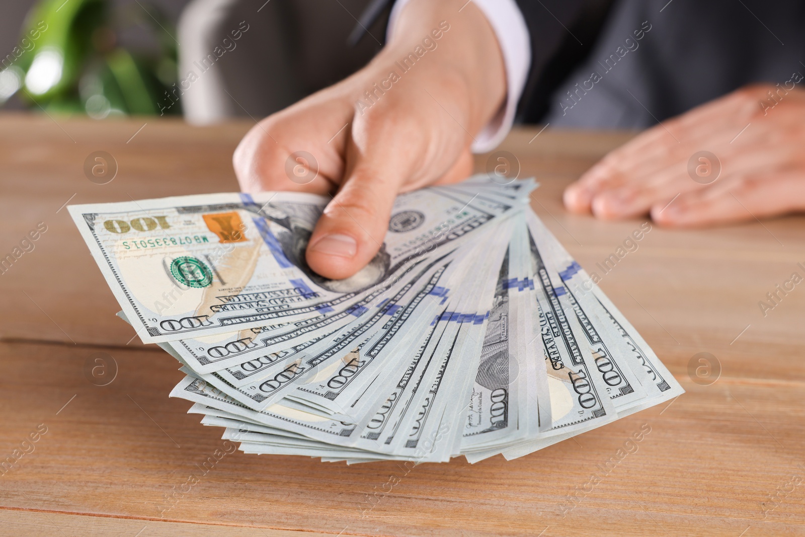 Photo of Money exchange. Man counting dollar banknotes at wooden table, closeup