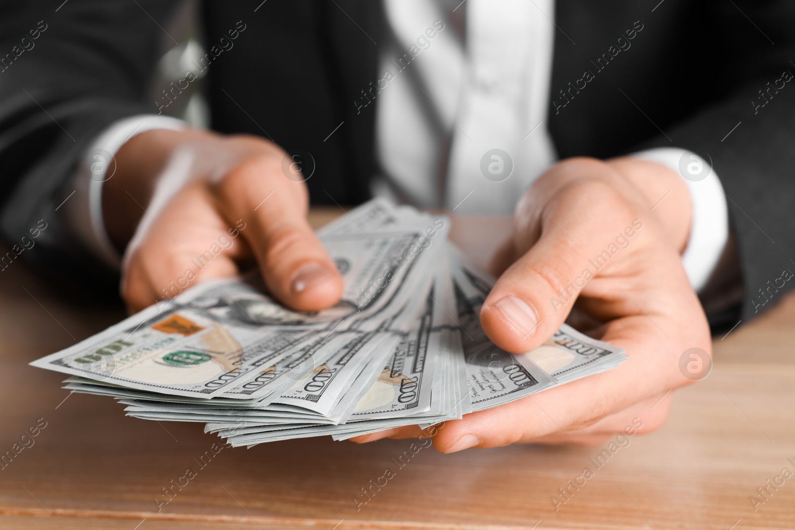 Photo of Money exchange. Man counting dollar banknotes at wooden table, closeup