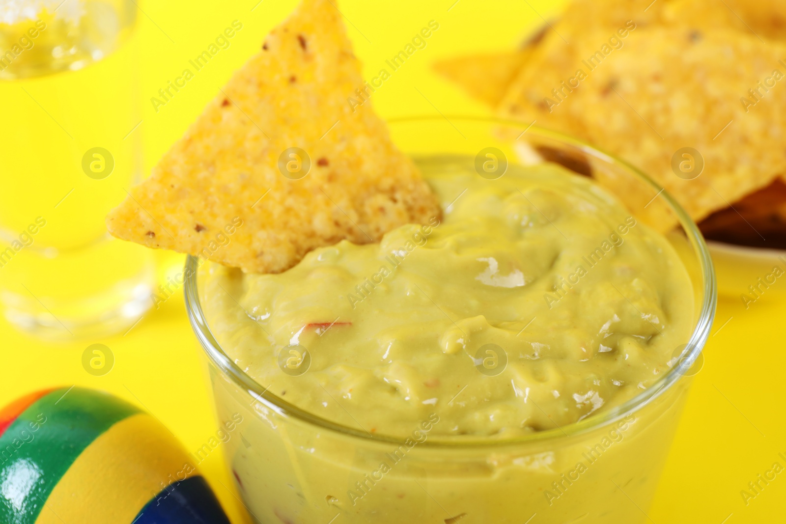 Photo of Delicious guacamole with nachos chip on yellow background, closeup