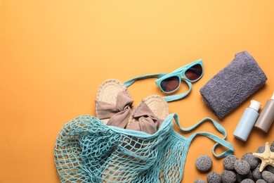 Photo of String bag and different beach accessories on pale orange background, flat lay. Space for text