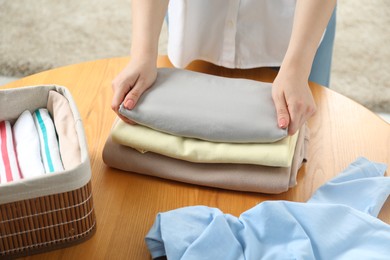 Photo of Woman folding clothes at wooden table indoors, closeup