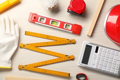Flat lay composition with building level and other construction tools on white wooden table