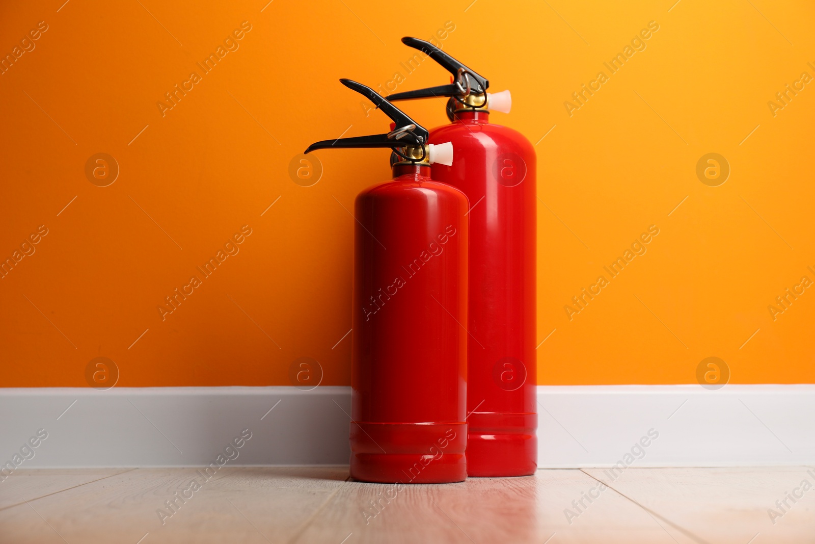 Photo of Fire extinguishers on floor near orange wall