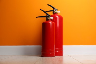 Photo of Fire extinguishers on floor near orange wall