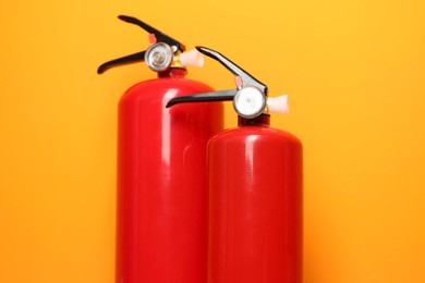 Photo of Two fire extinguishers on orange background, closeup