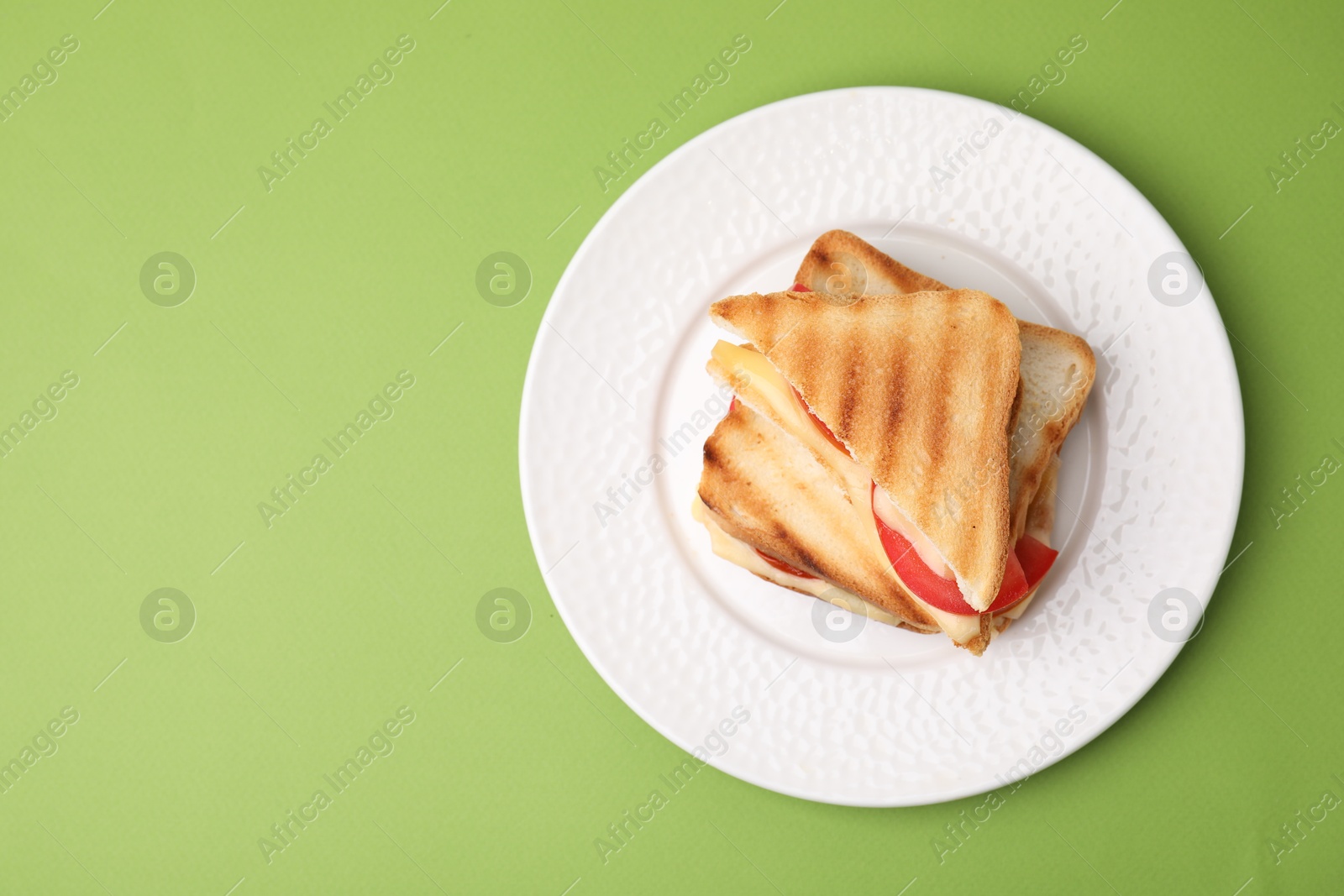 Photo of Pieces of toasted bread with melted cheese and tomato on green table, top view. Space for text